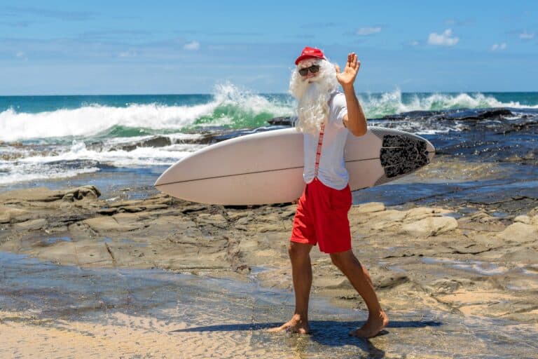 Santa Claus holds gift boxes with the ocean on backgraund